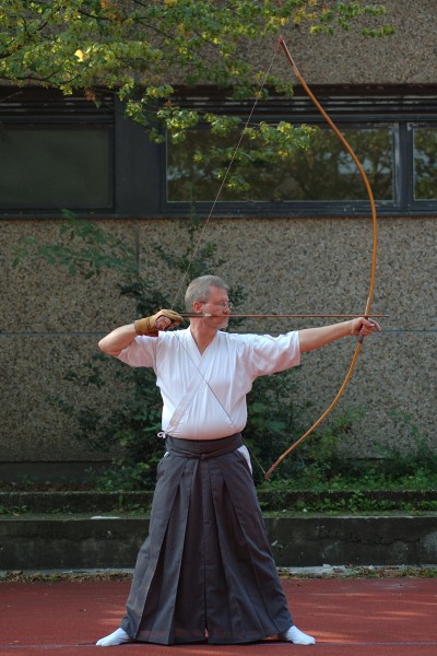 A man practicing a kyudo shot.