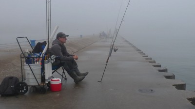Tyler Harmon of Eau Claire, Michigan is an experienced, well-geared pier angler. Here he waits for a summer steelhead to take a bobber down.