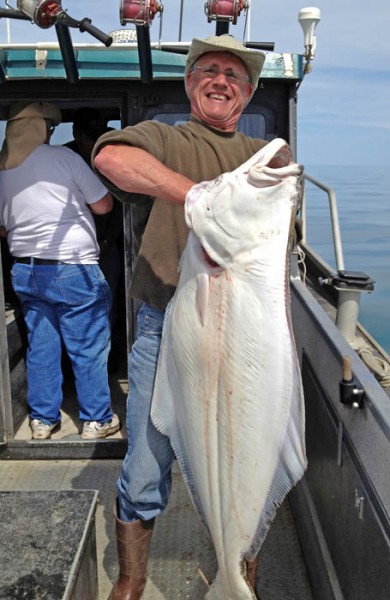 Jim Rather hoists up a 60-pound halibut he caught in Alaska’s Cook Inlet. It was the second-largest fish caught by his five-man Wisconsin party.