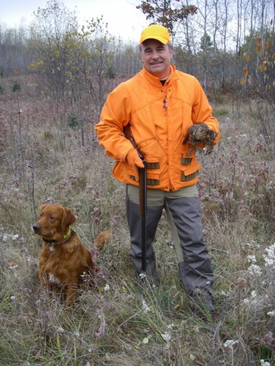 Jerry Dennis poses with a grouse retrieved by Gabe the golden retriever.