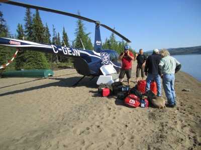 The anglers stand around their helicopter with gear piled up. 