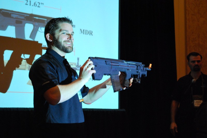 A smiling Desert Tech employee holds up the .223 MDR-C for display.