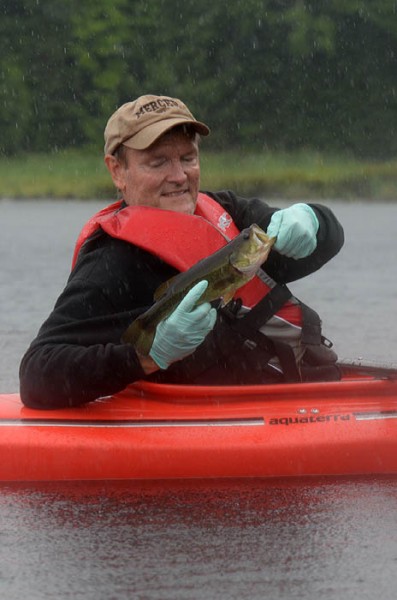 Larry Keen prepares to release a largemouth bass after catching it during a heavy downpour in Iron County on July 27.