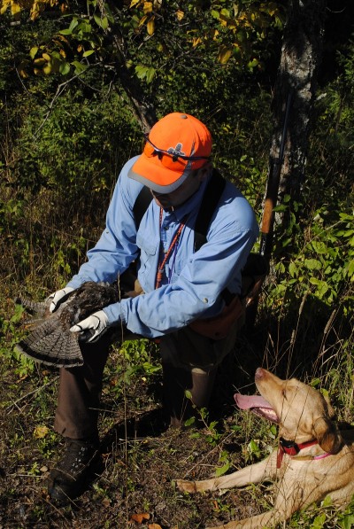 Ric Heller shows off a grouse to his Lab.