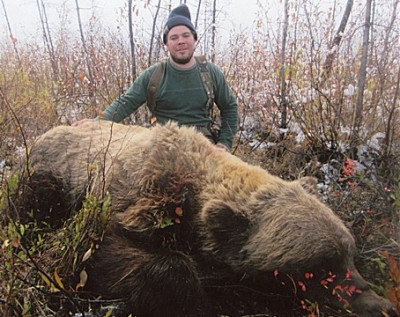 Larry Fitzgerald poses with the largest grizzly bear taken by a hunter. It was bagged in 2013 near the Totatlanika River, Alaska.