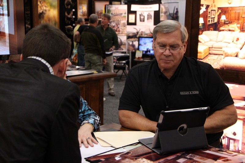 Tom Julian works with an attendee at the Dallas Safari Club convention and expo.
