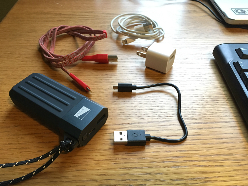 The Cascade Powerbank 5200 comes with a USB to USB Micro Charging Cable (black). The author has also been field-testing the Neve Micro USB cable (red). Also shown are the white charging cable and wall adapter that came with the author’s iPhone SE.